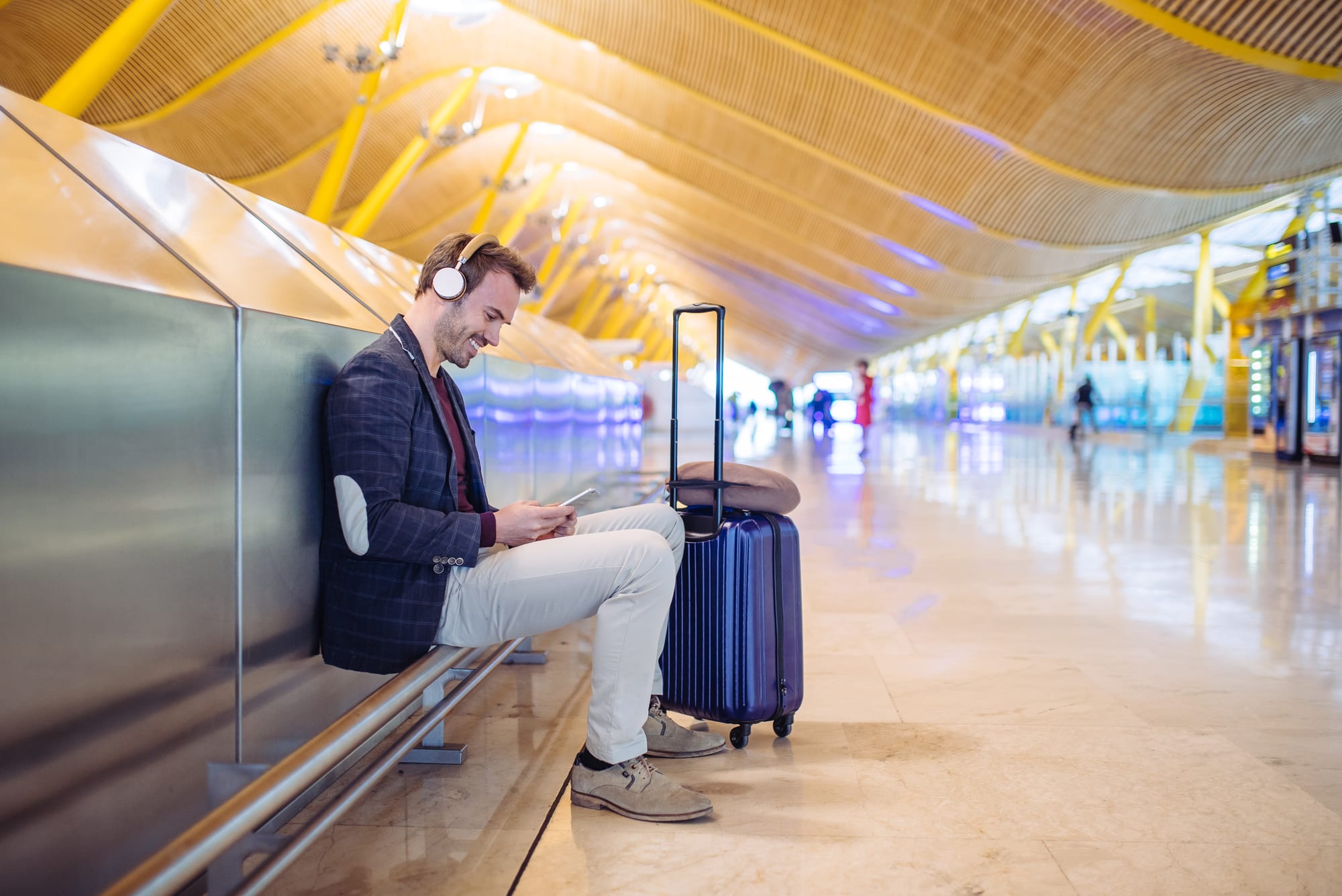 Traveler with electronic device, noice cancelling headphones and neck pillow. The best tech gadgets for travelers improve time spent away from home.